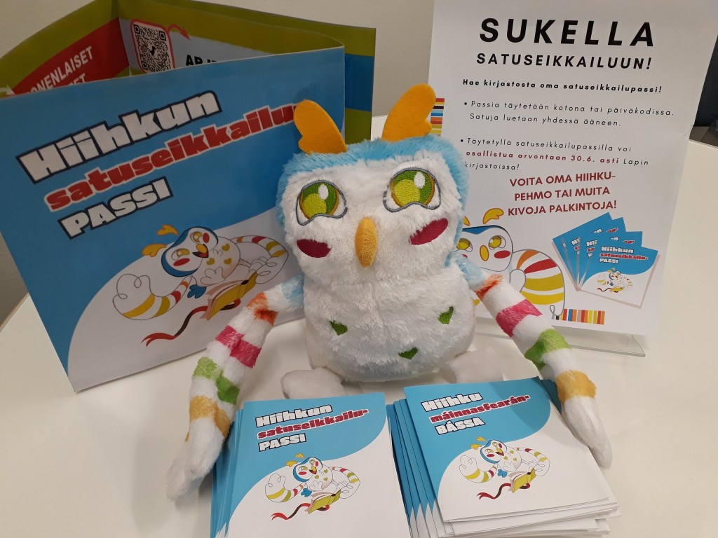 Hiihku-pehmolelu ja jaossa olevia Hiihkun satuseikkailupasseja suomeksi ja pohjoissaameksi.