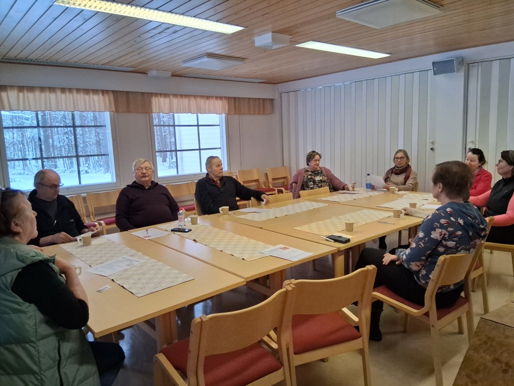 Ihmisiä pöydän ympärillä istumassa